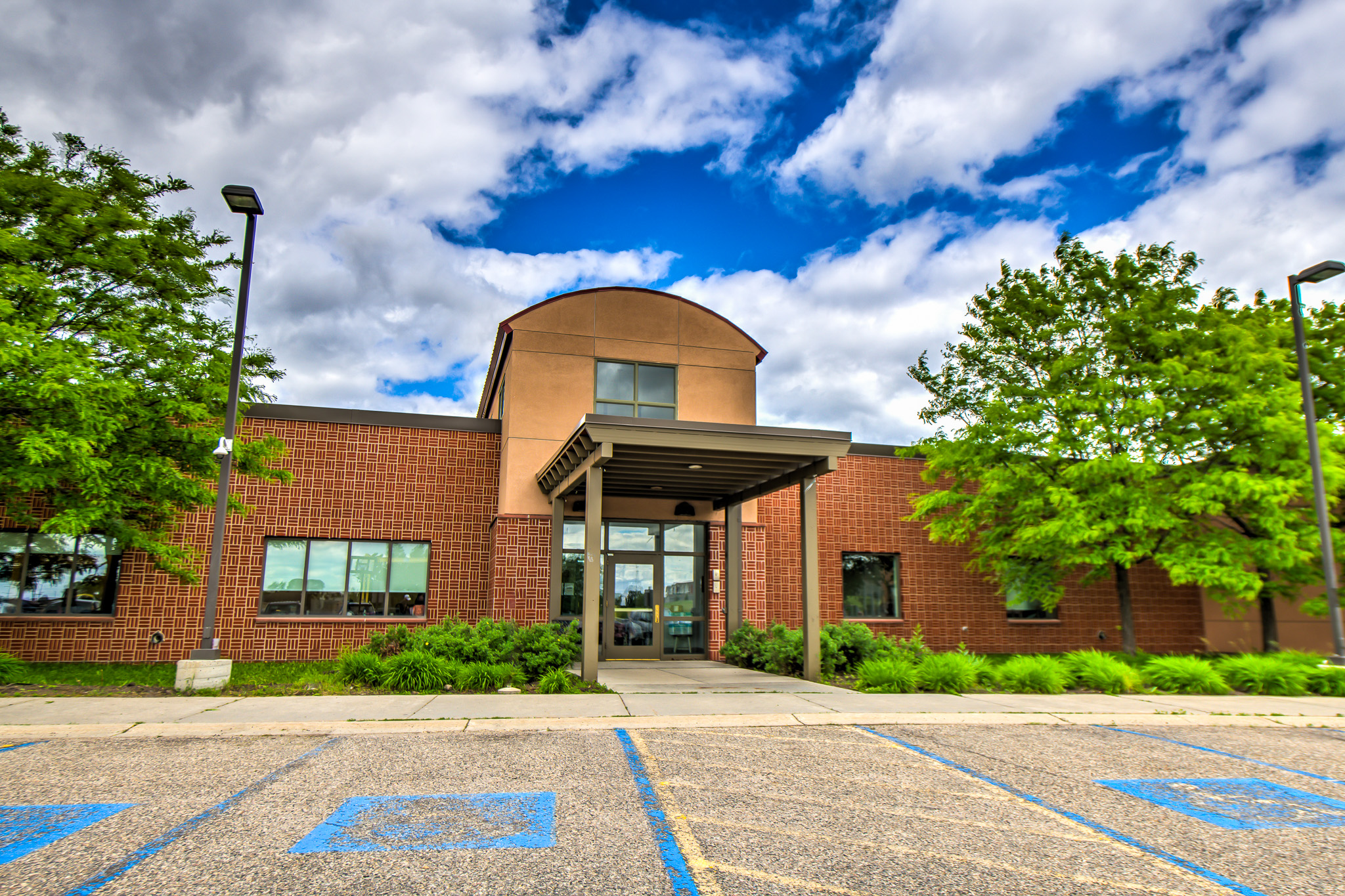 Brick-and-stucco building with blue sky and greenery