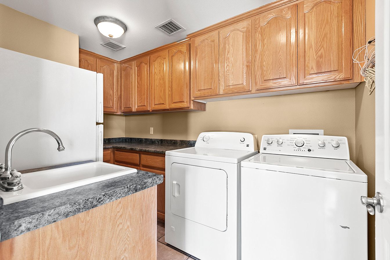 Laundry room with washer, dryer, and wooden cabinets