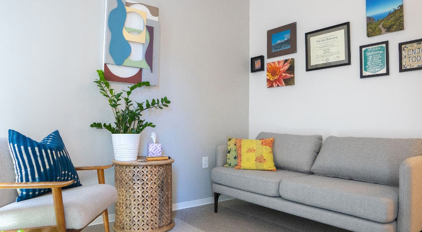 Counseling room with gray sofa, chairs, plants, and artwork