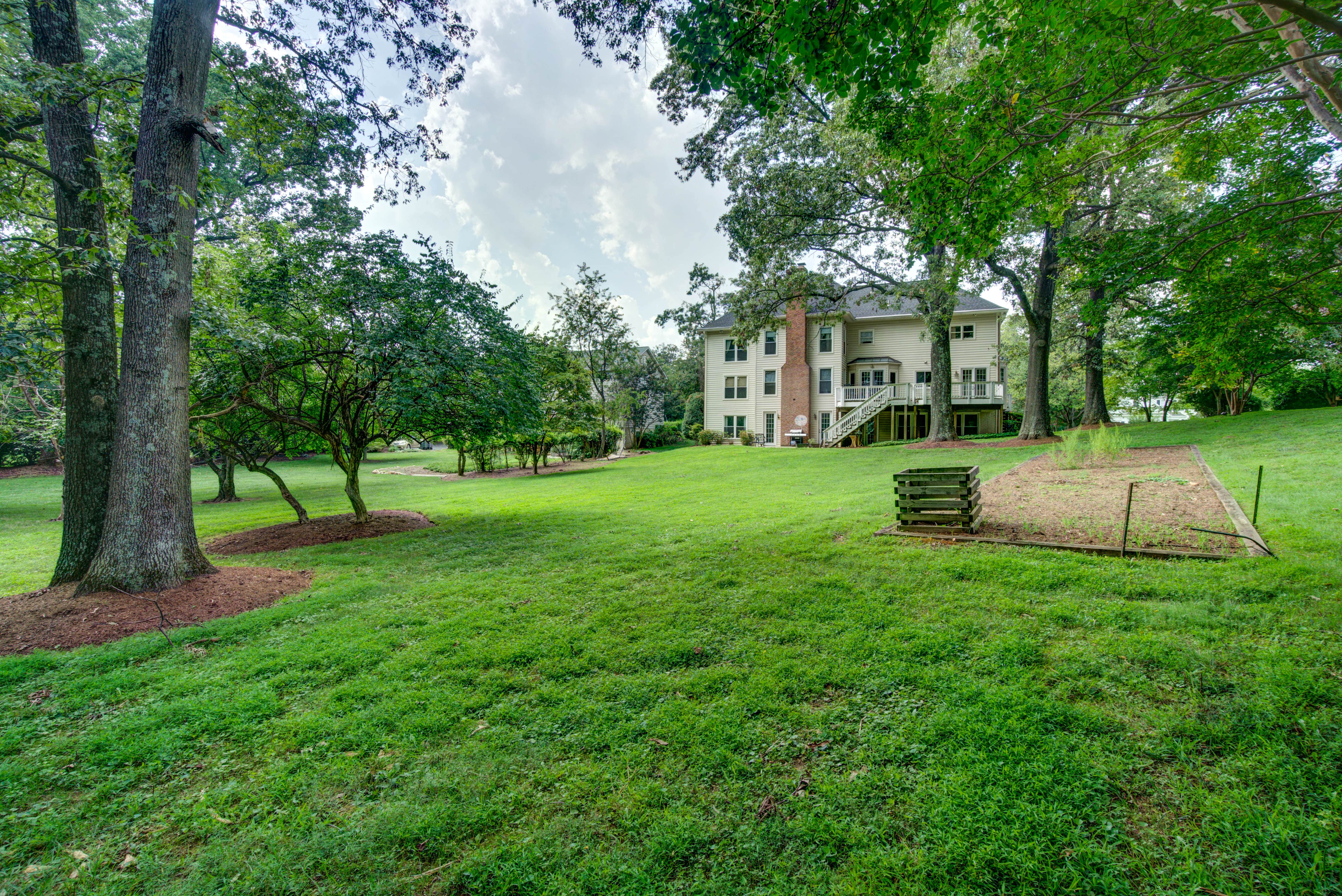 Large grassy backyard with garden and trees