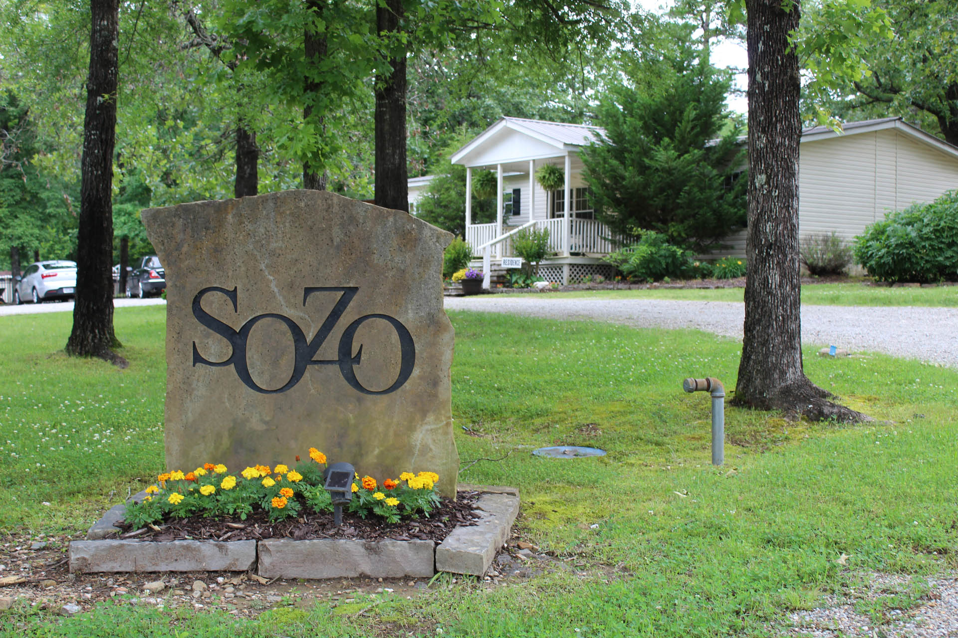 Stone entrance sign for SOZO Recovery Center on landscaped lawn