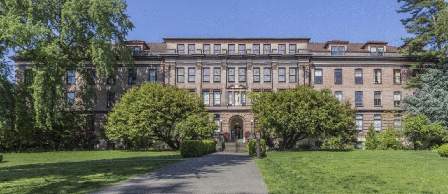 Grand historic brick building with arched entry and manicured lawn