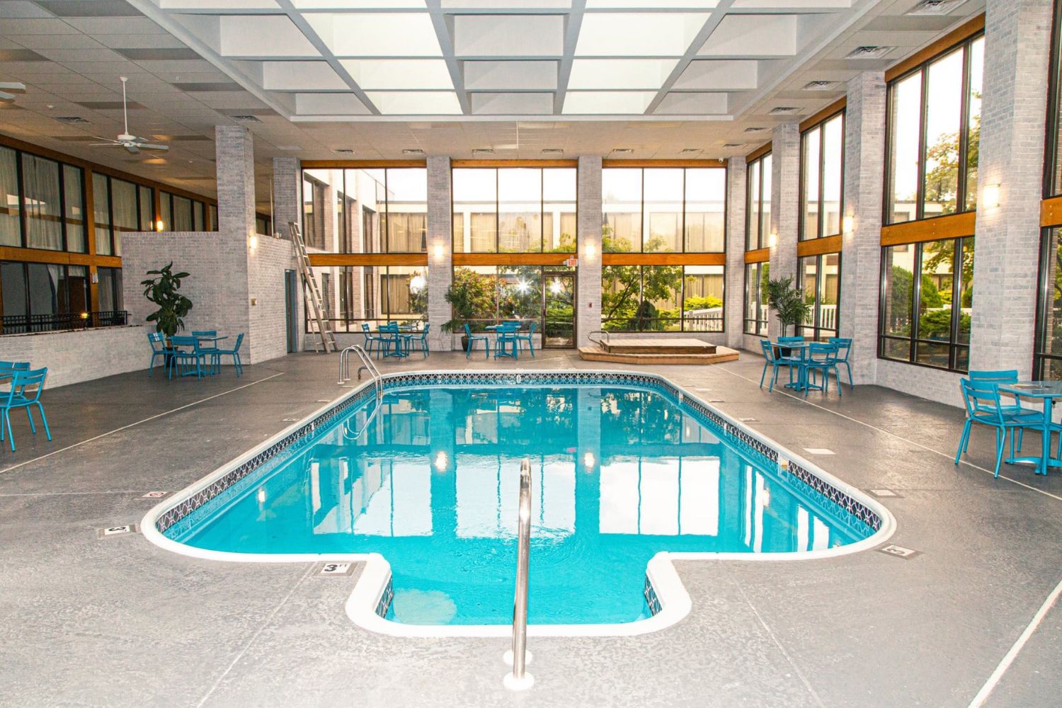 Pool area with tall windows and seating,