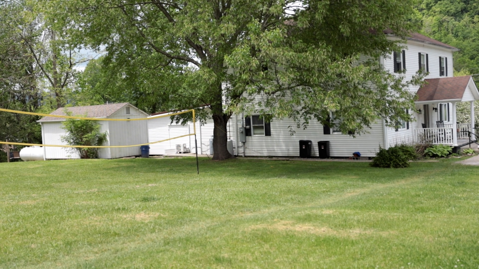 Grassy yard with volleyball net and large trees