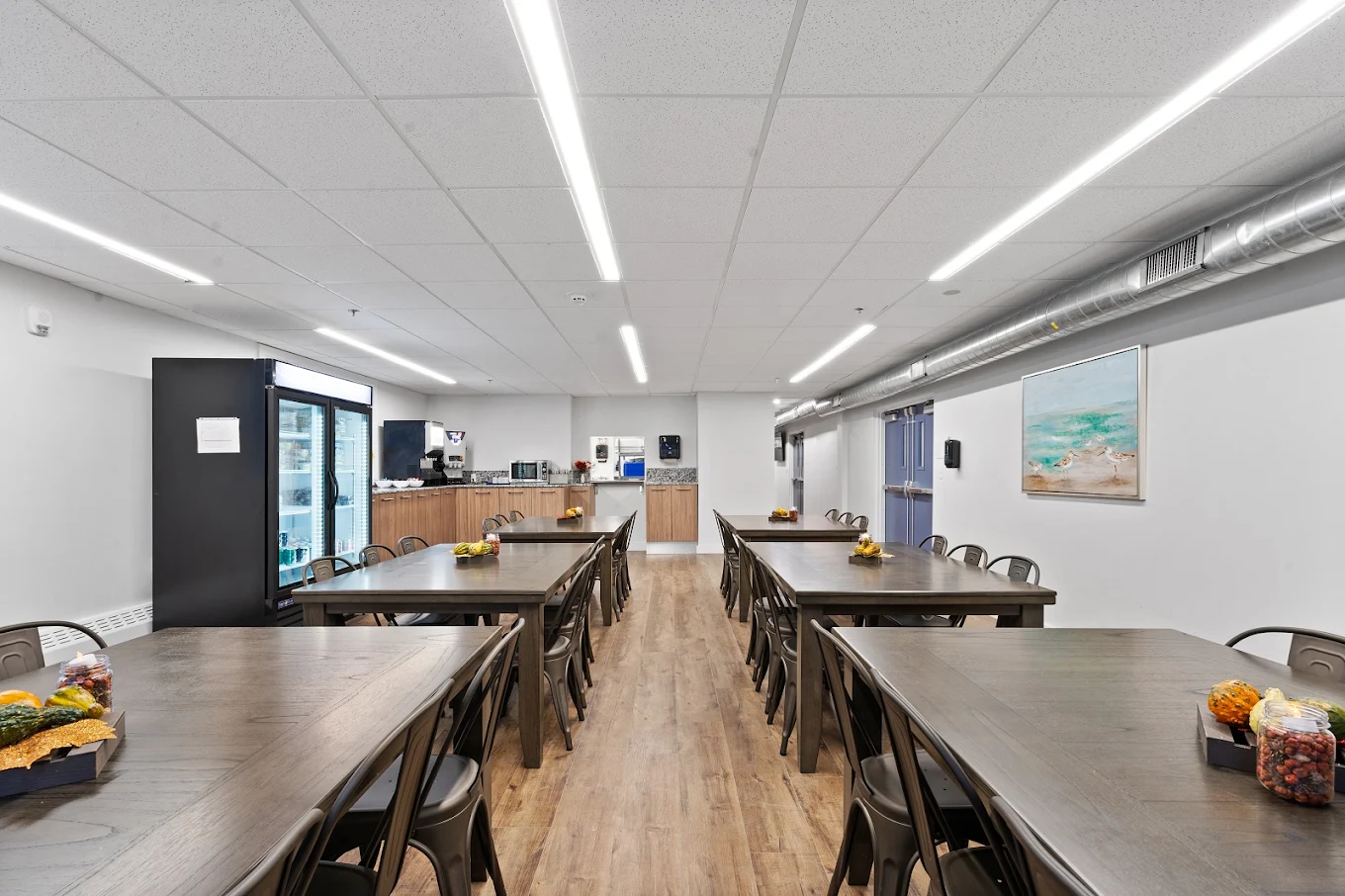 Cafeteria-style dining area with long tables, chairs, and food service stations
