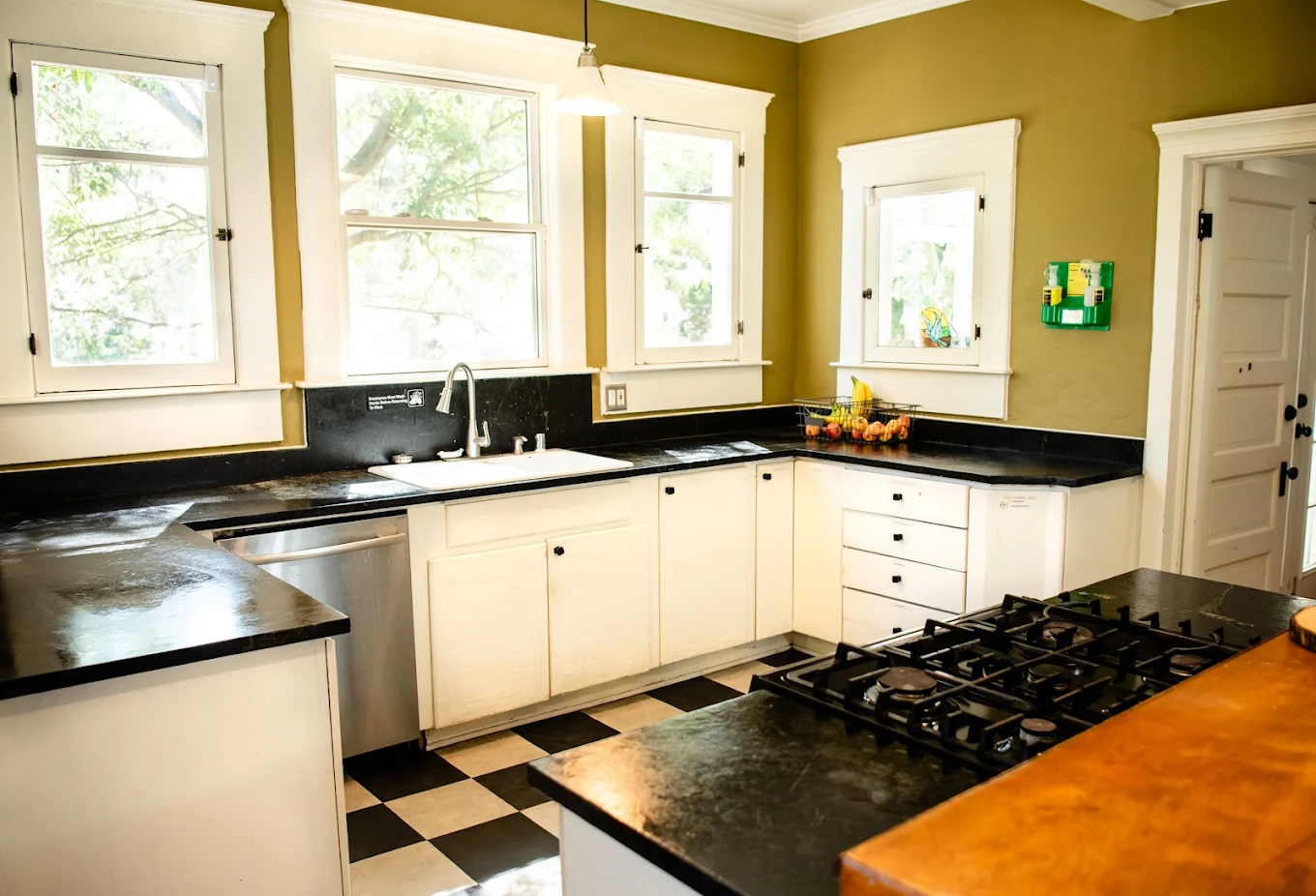 Bright kitchen with white cabinetry, black countertops, and checkered flooring