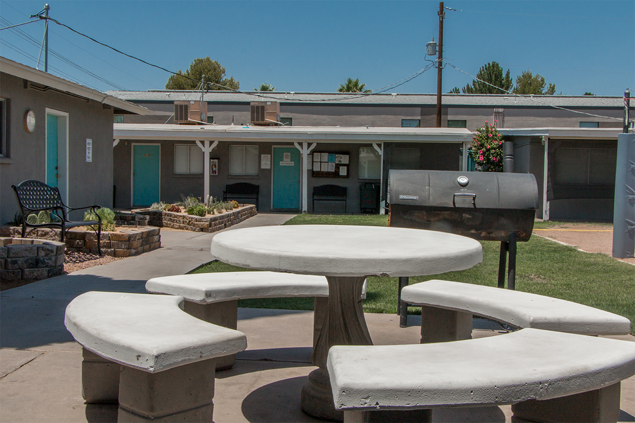Courtyard with round concrete picnic table, benches, and BBQ grill