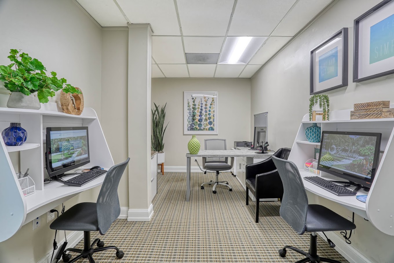 Computer workspace with desk, chairs, and indoor plants