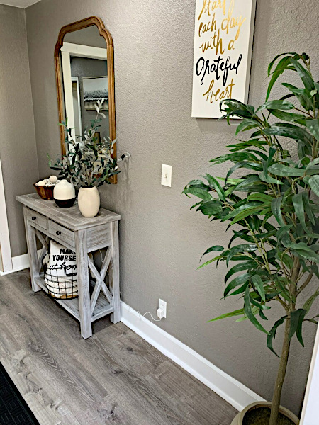 Entryway with small table, plant, and decorative wall sign