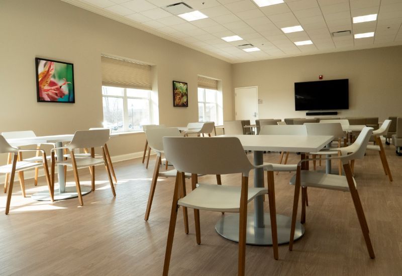 Bright meeting room with white tables, chairs, and wall TV