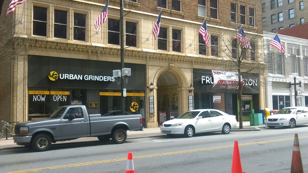 Storefronts with Urban Grinders sign and building archway