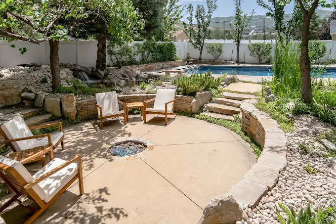 Firepit area beside pool and garden landscaping