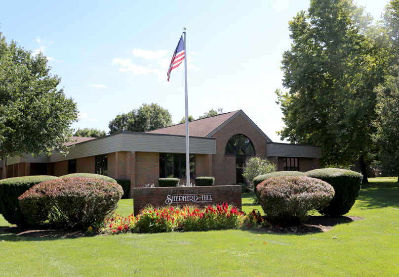 Brick treatment center with lawn, shrubs, and flagpole out front