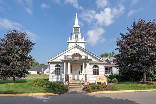 White chapel with steeple surrounded by trees