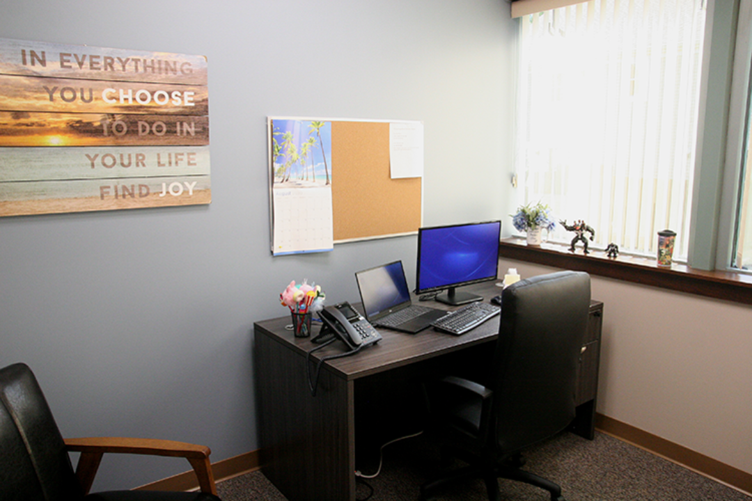 Private consultation room with desk, computers, and chairs
