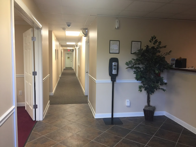 A hallway in a rehab facility with beige walls and a hand sanitizer station.