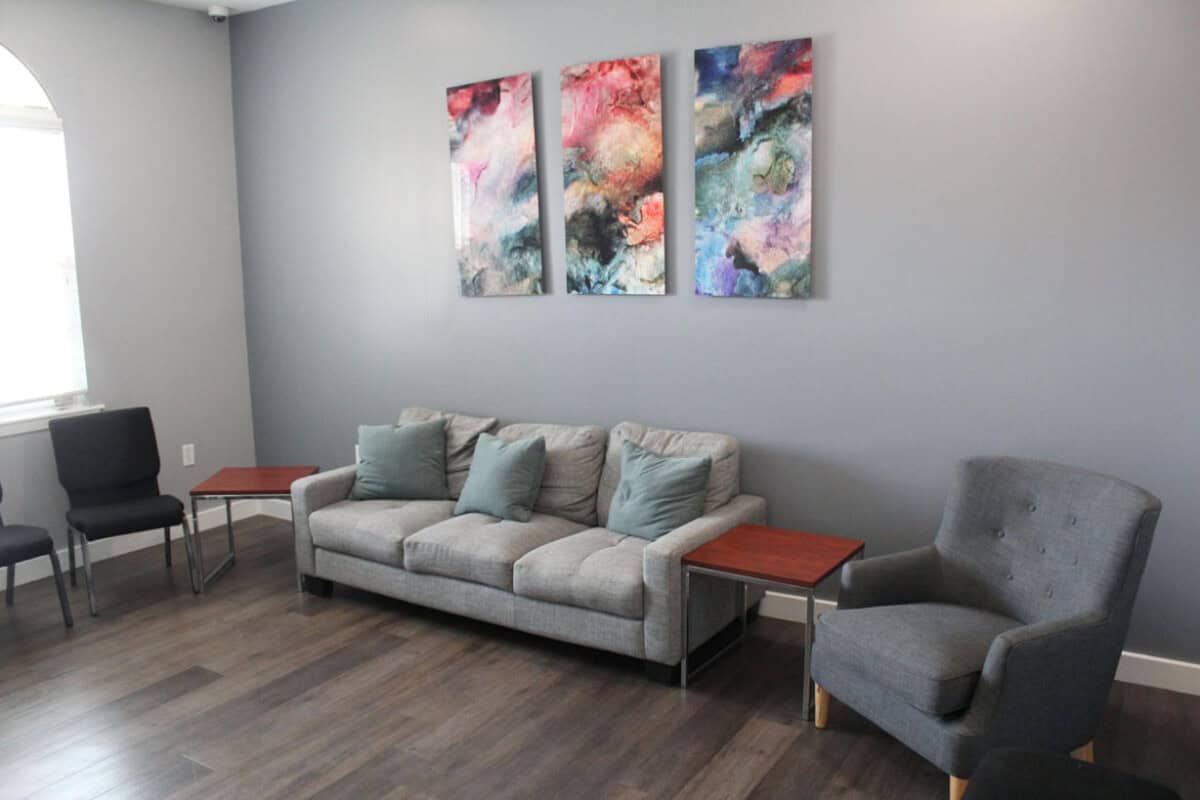 Therapy room with a couch, chairs and wall art.