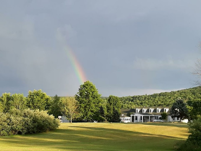 Rainbow above green lawn with rehab center in background