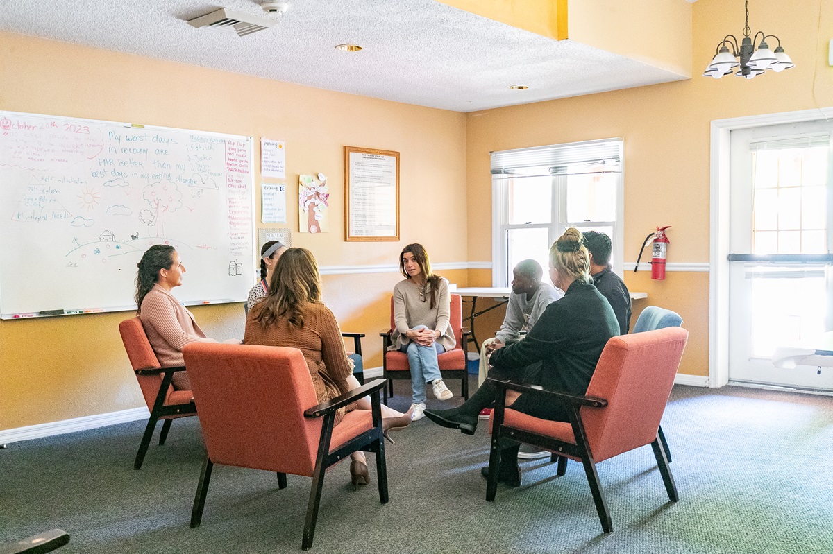 People seated in a therapy circle in a cozy meeting room
