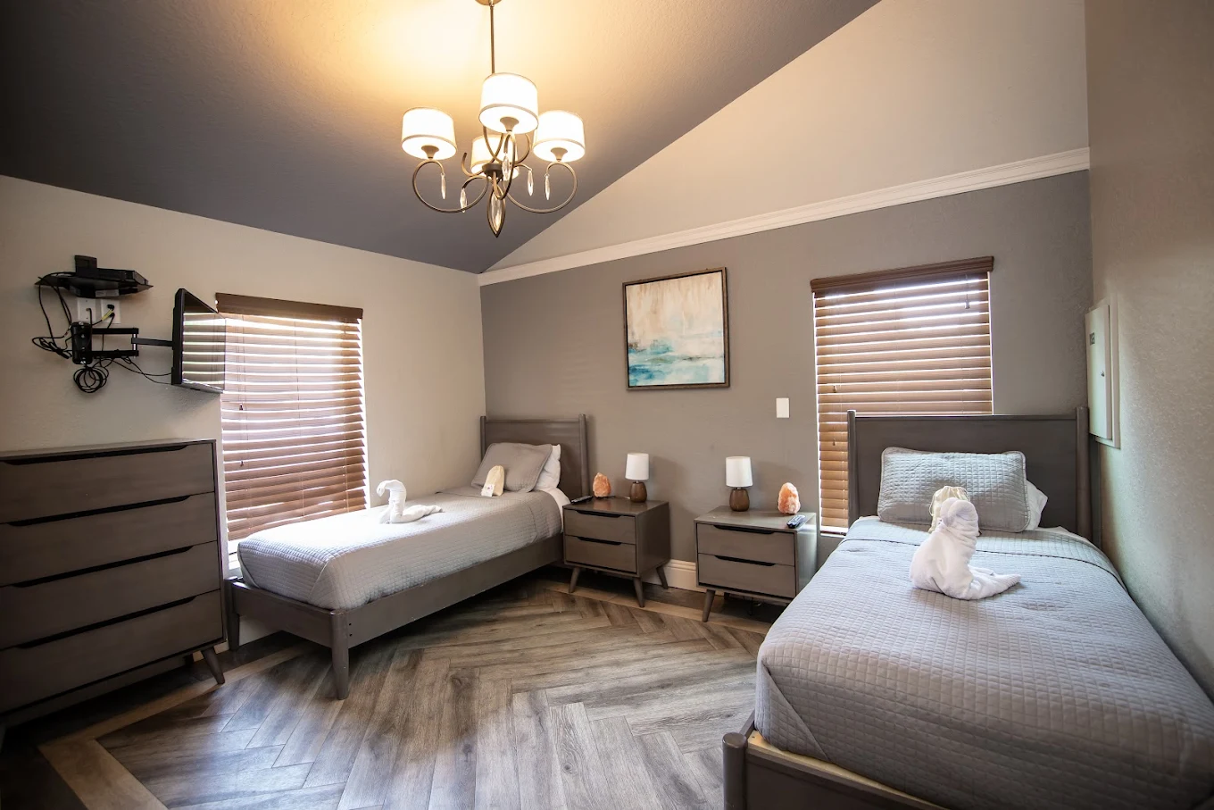 Two beds with neutral bedding and wood furniture