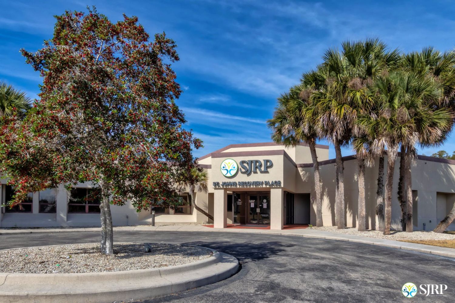 Rehab facility exterior with palm trees.