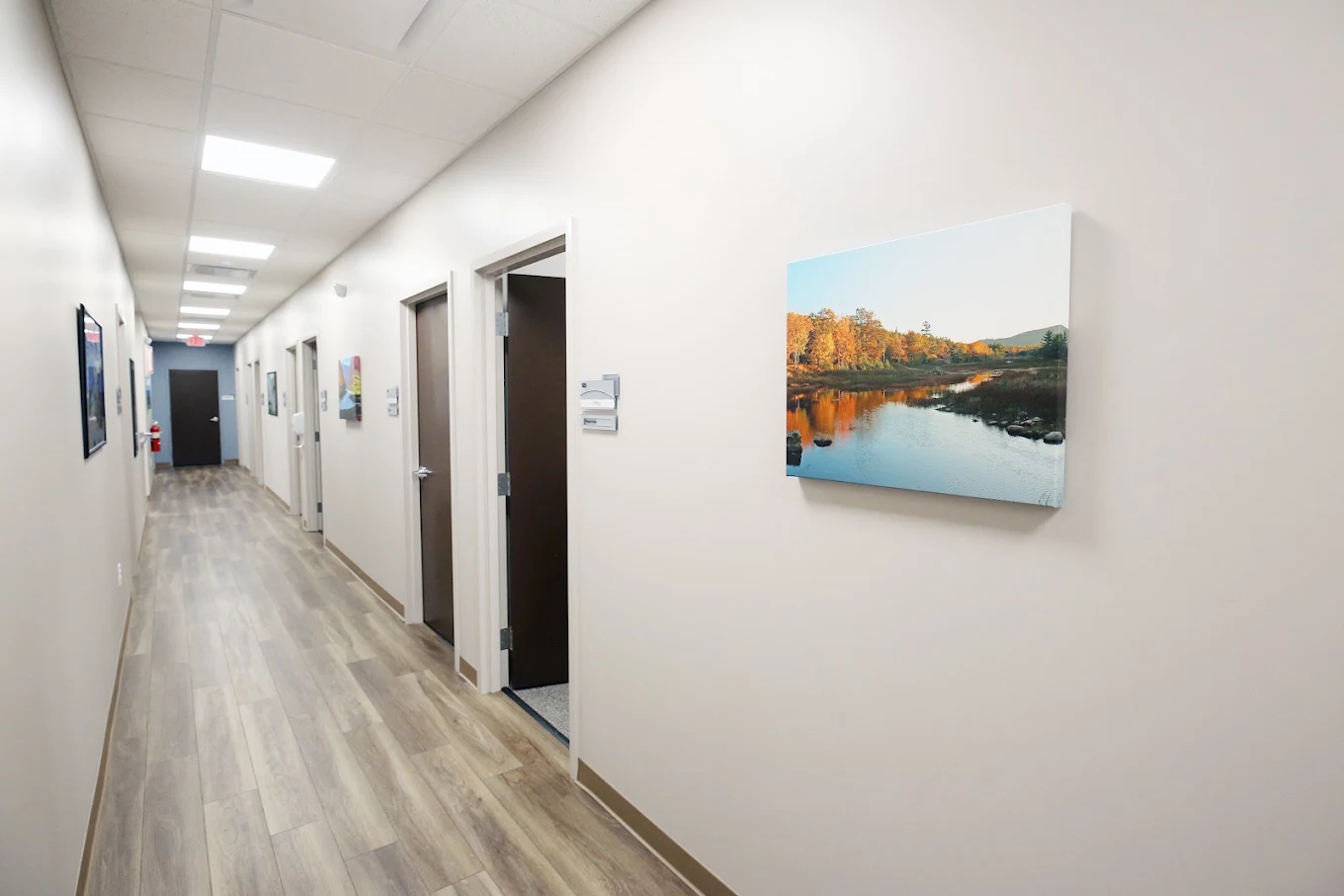 BrightView Elyria treatment center hallway with clinical room doors, wood-look flooring, and landscape artwork