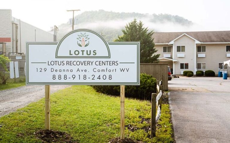 Entrance sign with building and hills in the background