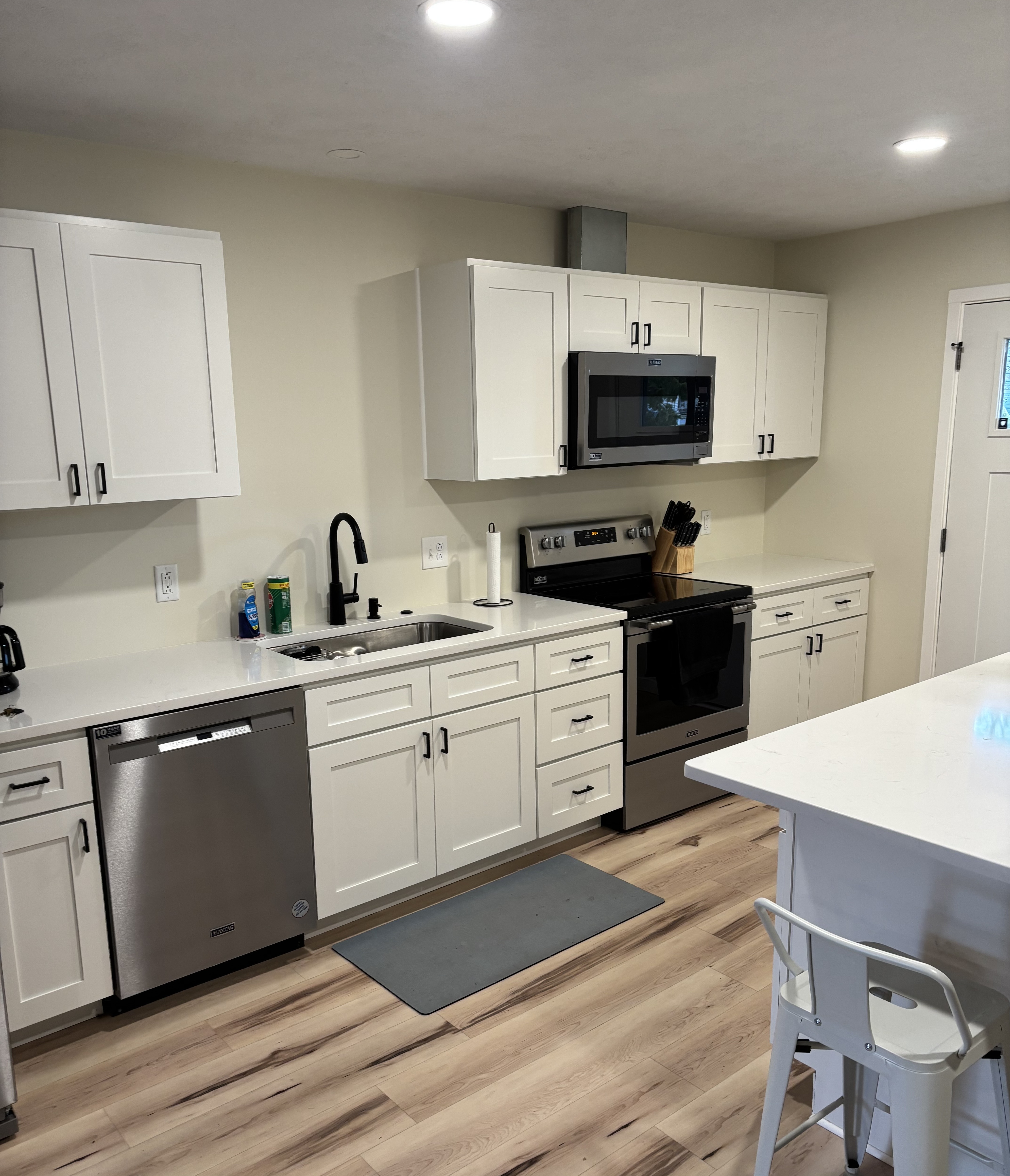 Open kitchen-living space with island, fridge, and tan armchairs.