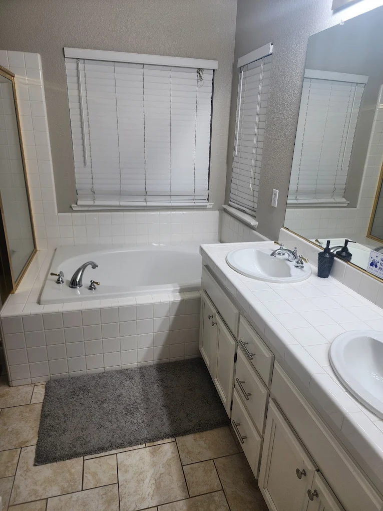 Rehab bathroom with tub, sinks, and large mirror
