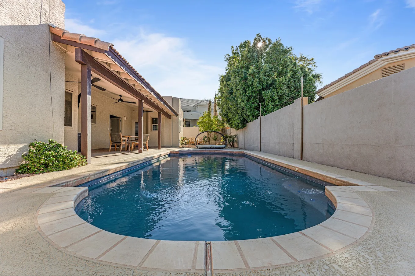 Outdoor swimming pool beside a covered patio and seating area.