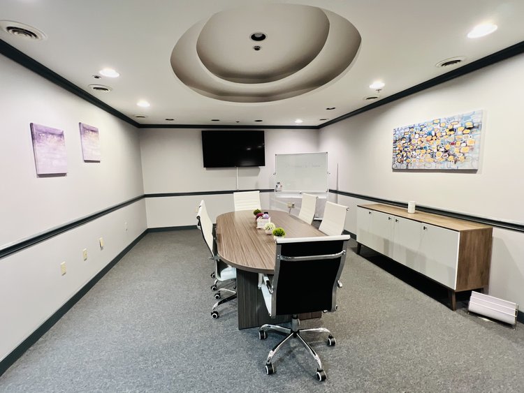  Oval table with white chairs and TV on wall