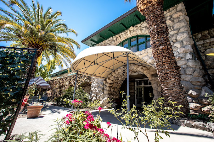 A rehab facility entrance with a canopy, flowers, and stone archways.