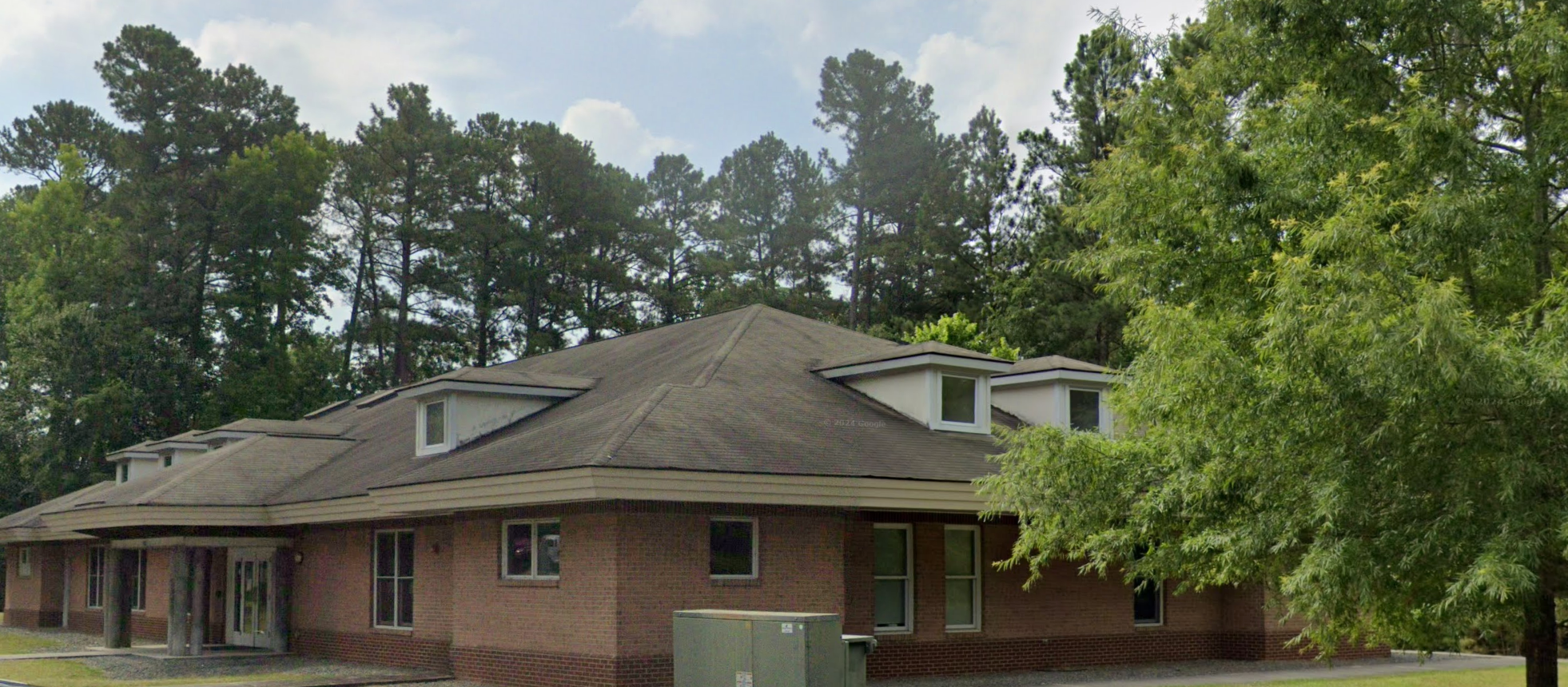 Freedom House Recovery Center Men's Residential Program, highlighting the building's architecture and natural surroundings with trees providing a serene setting.