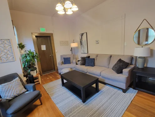 Cozy lounge with sofa, chairs, rug, and wall art