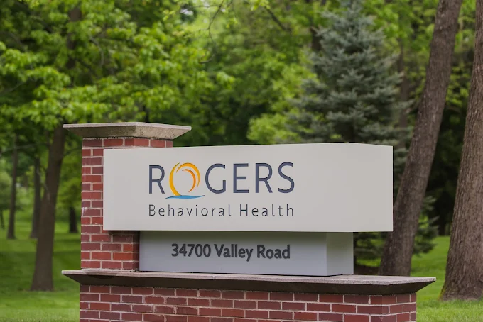 Rogers Behavioral Health sign with address in wooded area