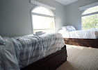 Two twin beds beside large arched windows in shared room