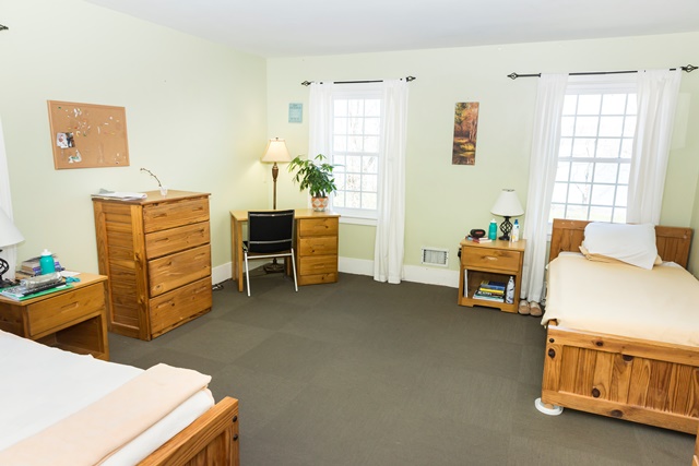 Shared residential bedroom with beds, desks, and windows