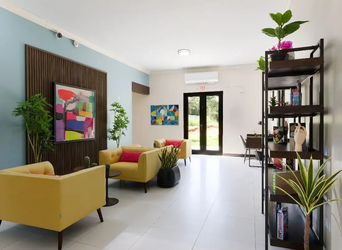 Lounge with yellow chairs, artwork, and indoor plants.