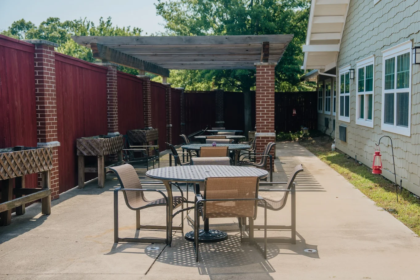 Outdoor patio seating under pergola with tables and chairs.