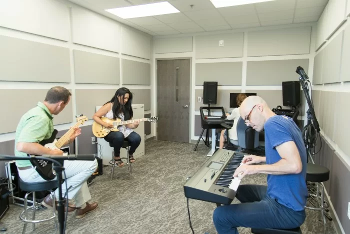 Group music session with guitars and keyboard in soundproof room