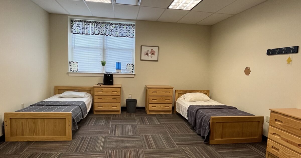 Two-bed rehab room with wood furniture and window