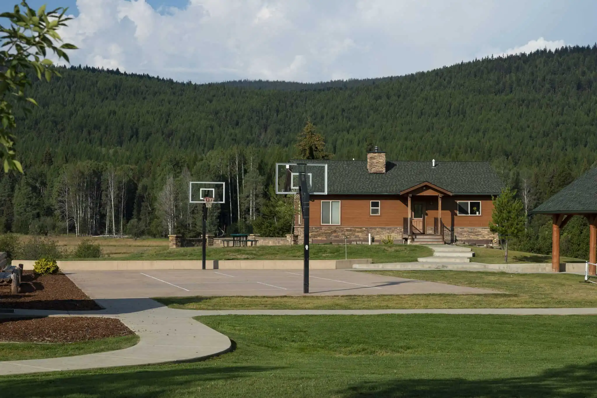 Outdoor basketball court with mountain forest backdrop