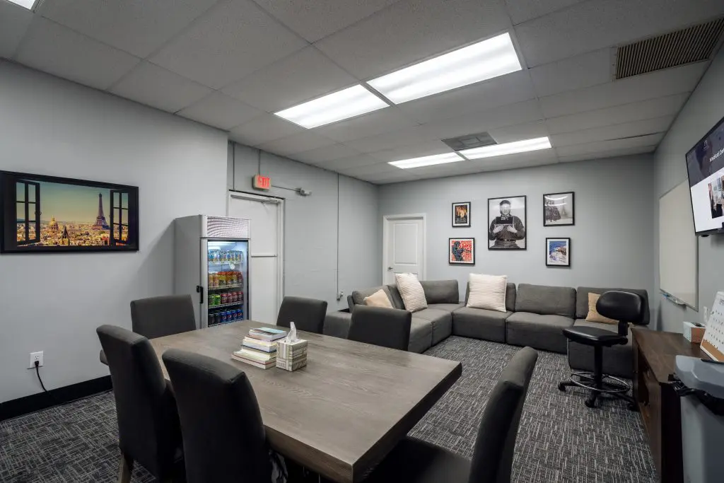 Large meeting room with couches, framed art, and a mini fridge