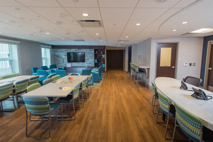 Open room with tables, chairs, and TV for group activities