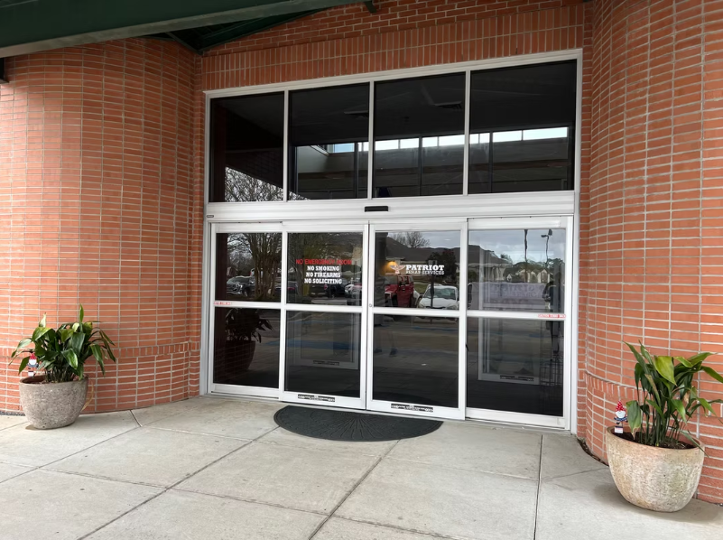 Main glass entrance of Patriot Rehab Services with signage and potted plants on either side