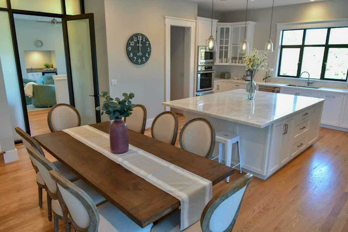 Dining table next to a kitchen island with pendant lights