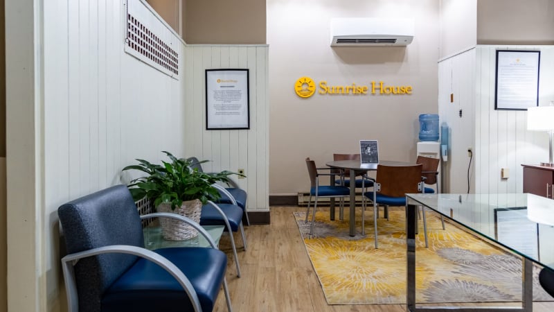 Waiting area at sunrise house with chairs and signage on the wall.