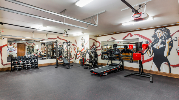 Fully equipped fitness room with mural walls, weights, treadmill, and strength training machines