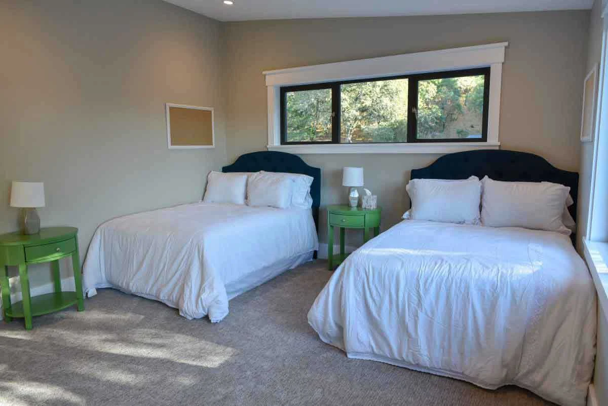 Two double beds with green nightstands and windows