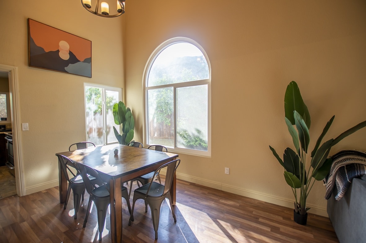 A dining area with a large arched window and green plants.